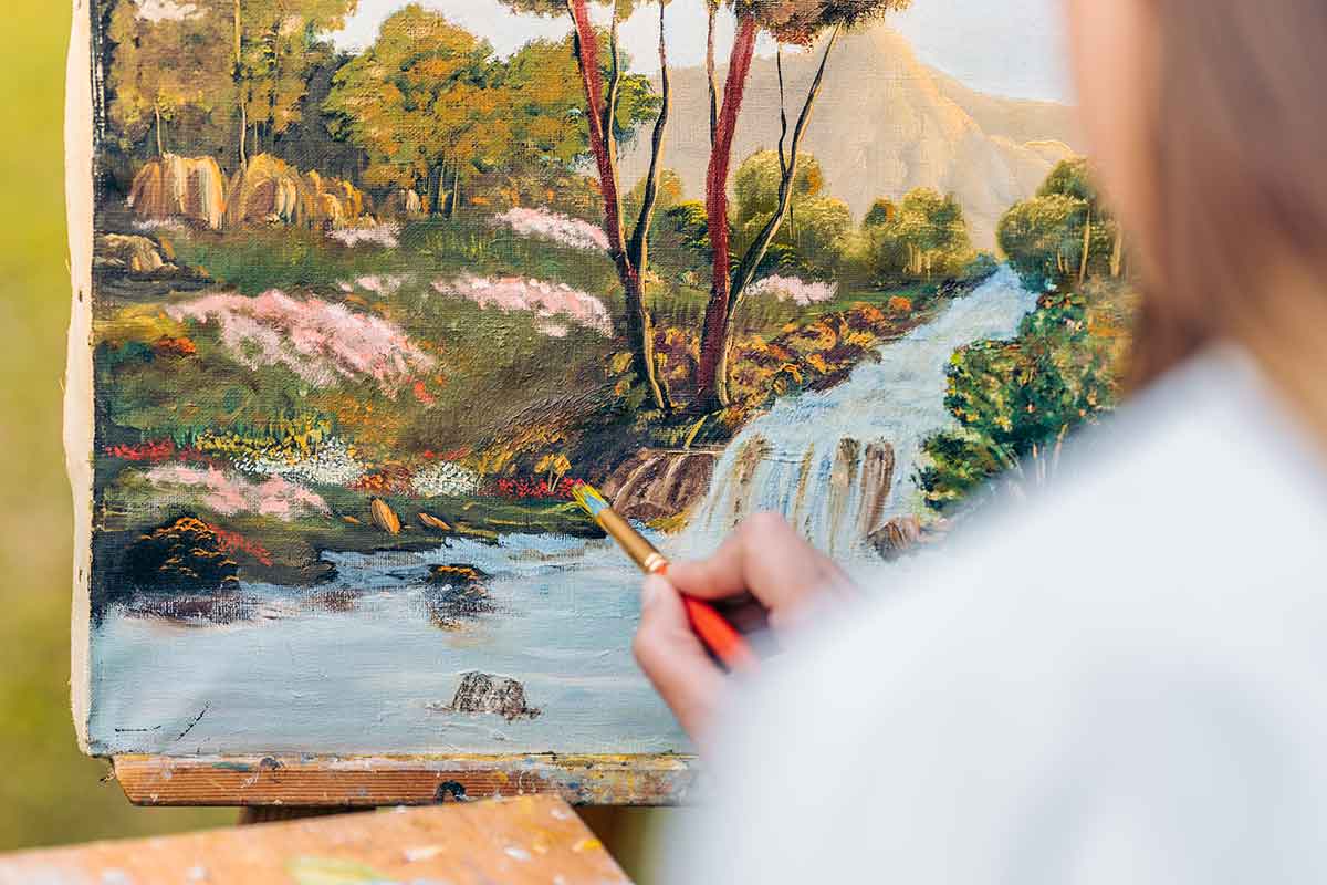 Artista che dipinge quadri di paesaggi e natura a olio su tela